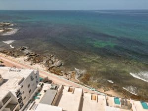 Beautiful coastal view of the ocean with rocky shoreline and beachfront properties. Isla Mujeres Mexico Property