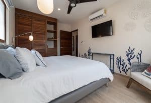 Modern bedroom with wooden accents, air conditioning, and ocean-inspired decor for a relaxing stay. Isla Mujeres Mexico Property