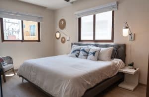 Modern bedroom with large windows, neutral decor, and cozy ambiance in a residential property. Isla Mujeres Mexico Property