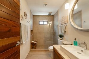 Modern bathroom with walk-in shower, wooden accents, and contemporary fixtures at Mundaca Real Estat. Isla Mujeres Mexico Property