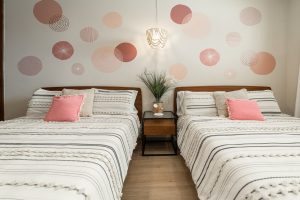 Modern bedroom with two beds, pink pillows, and stylish wall decor in a contemporary home.