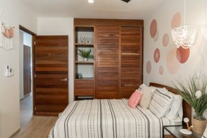 Modern bedroom with wooden closet doors, decorative wall art, and cozy bedding, showcasing stylish i.