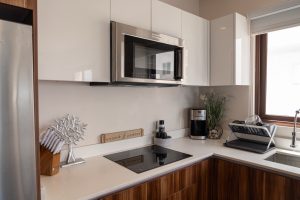 Modern kitchen with white cabinets, stainless steel microwave, and black induction cooktop at Mundac.