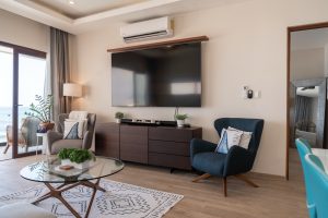 Modern living room with large TV, comfortable chairs, and balcony view in a luxury property.