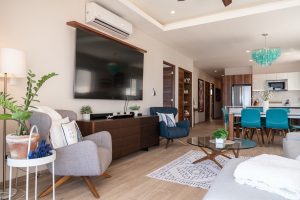 Modern living room with flat-screen TV, stylish furniture, and open-concept kitchen in a luxury prop.