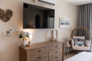 Modern living room with wall-mounted TV, wooden console, and cozy seating area featuring decorative.