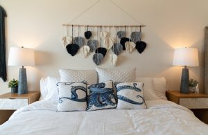 Cozy bedroom with decorative wall hanging and ocean-themed pillows, perfect for a relaxing stay.