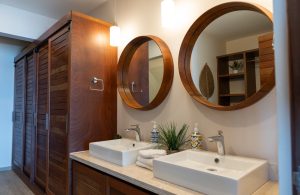 Modern bathroom with double sinks, wooden accents, and stylish mirrors at Mundaca Real Estate.