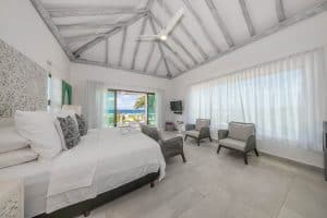 Relaxing bedroom with ocean view, white decor, and modern furnishings at Mundaca Real Estate propert. Isla Mujeres Mexico Property