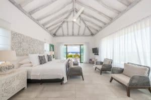 A lush, airy bedroom with ocean views, white decor, and elegant furniture in a tropical resort setti. Isla Mujeres Mexico Property