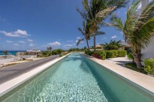 Luxury beachfront pool at Mundaca Real Estate in Mexico, surrounded by palm trees and tropical lands. Isla Mujeres Mexico Property