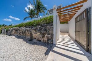 Modern beachfront property entrance with tropical landscaping and wooden pergola, Mundaca Real Estat. Isla Mujeres Mexico Property