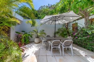Relaxing outdoor patio with garden, table, chairs, and umbrella at Mundaca Real Estate property. Isla Mujeres Mexico Property
