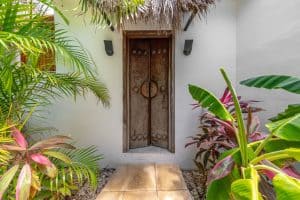 Ancient wooden door surrounded by lush tropical plants in a serene outdoor setting. Isla Mujeres Mexico Property