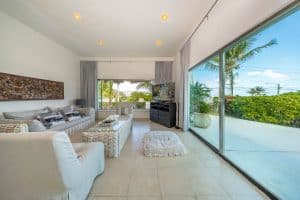 Bright living room with large glass doors overlooking lush outdoor greenery and tropical palm trees. Isla Mujeres Mexico Property