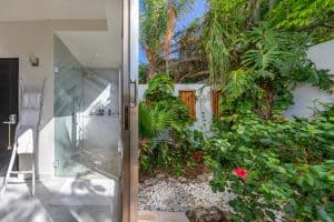 Bright indoor bathroom with glass shower and lush tropical garden view. Isla Mujeres Mexico Property
