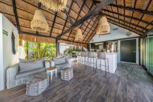 Relaxing tropical outdoor living space with thatched roof, wicker furniture, and lush greenery at Mu. Isla Mujeres Mexico Property