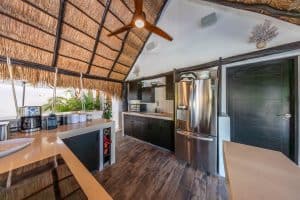 Modern kitchen with stainless steel appliances and tropical thatched roof ceiling at Mundaca Real Es. Isla Mujeres Mexico Property