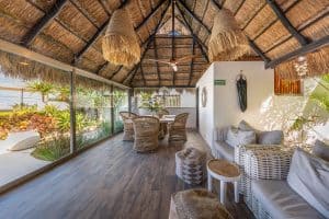 Elegant tropical lounge with wicker furniture and lush garden views at Mundaca Real Estate. Isla Mujeres Mexico Property