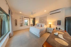 Relaxing bedroom with white bedding, natural light, and coastal decor in a tropical property. Isla Mujeres Mexico Property