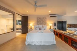 Elegant bedroom with white bedding, wooden furniture, and ambient lighting at Mundaca Real Estate pr. Isla Mujeres Mexico Property