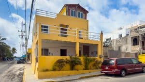 Modern yellow residential building with multiple balconies in an urban area. Isla Mujeres Mexico Property