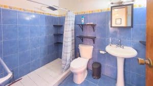Bathroom with blue tiles, shower, toilet, and sink in a residential property. Isla Mujeres Mexico Property