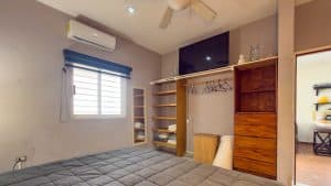 Modern bedroom with wooden closet and window, ideal for real estate listings. Isla Mujeres Mexico Property