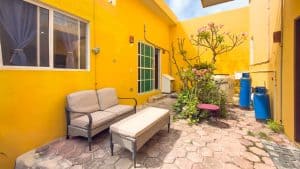 Relaxing outdoor patio with vibrant yellow walls, garden, and seating area in a Mexican property. Isla Mujeres Mexico Property