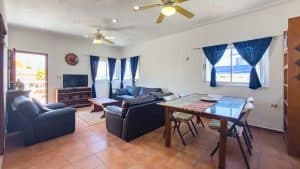 Modern living room with blue curtains, sofa set, and dining area in a bright, spacious home. Isla Mujeres Mexico Property