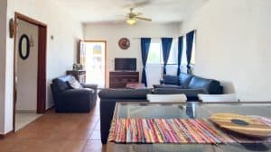 A comfortable living room with blue curtains, sofa set, and a flat-screen TV in a sunny home. Isla Mujeres Mexico Property
