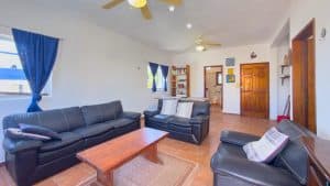 Modern living room with black leather sofas, wooden coffee table, and bright natural light in a Cost. Isla Mujeres Mexico Property