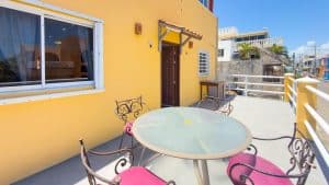 Modern yellow house with outdoor patio and seating area in a vibrant neighborhood. Isla Mujeres Mexico Property
