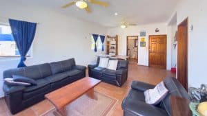 Modern living room with black sofas, wooden coffee table, and bright natural light from windows with. Isla Mujeres Mexico Property