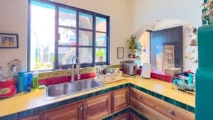 A comfortable kitchen with colorful accents and natural light from large window. Isla Mujeres Mexico Property