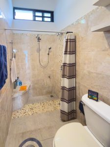 Modern beige tiled bathroom with walk-in shower and shower curtain. Isla Mujeres Mexico Property