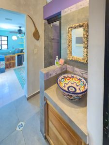 Bright bathroom with colorful vessel sink, decorative mirror, and modern fixtures in a stylish home. Isla Mujeres Mexico Property