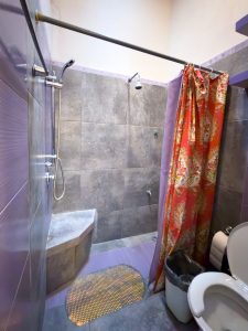 Modern walk-in shower with stone bench and colorful curtain in a contemporary bathroom. Isla Mujeres Mexico Property