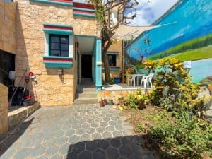 Modern Mexican-style house with stone facade and colorful accents, surrounded by garden and outdoor. Isla Mujeres Mexico Property