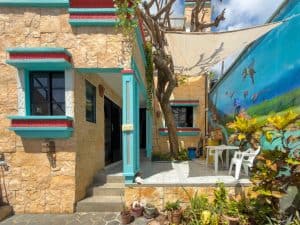 Charming Mexican-style house with colorful accents and outdoor seating in a lush garden setting. Isla Mujeres Mexico Property