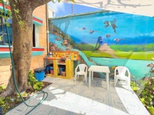 Outdoor patio with colorful mural, chairs, and table at Mundaca Real Estate property. Isla Mujeres Mexico Property