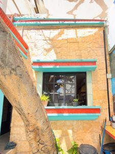 Modern building facade with colorful accents and large window in a tropical setting. Isla Mujeres Mexico Property