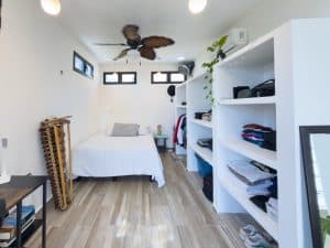 Modern bedroom with white walls, wooden flooring, and built-in shelves for storage. Isla Mujeres Mexico Property