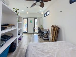 Modern bedroom with white walls, wooden flooring, and ample natural light from large windows. Isla Mujeres Mexico Property