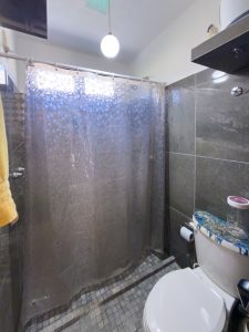 Modern bathroom with gray tiles and shower curtain in a residential property. Isla Mujeres Mexico Property