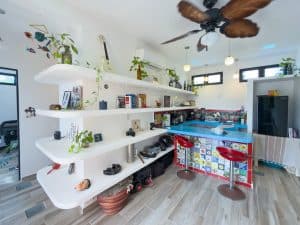 Modern living room with white shelves, colorful tiled bar, and ceiling fan in a bright, airy space. Isla Mujeres Mexico Property