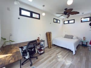 Modern bedroom with minimalist decor, ceiling fan, and natural light from small windows, ideal for r. Isla Mujeres Mexico Property